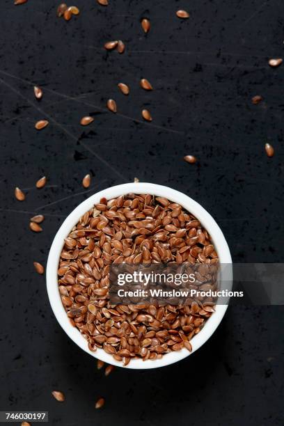 bowl full of flax seeds on black background - semilla-de-lino fotografías e imágenes de stock