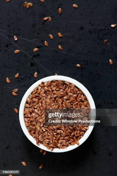 bowl full of flax seeds on black background - flax seed stock pictures, royalty-free photos & images