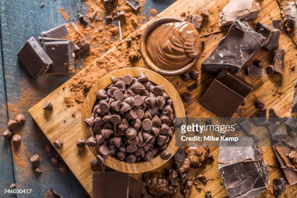 various chocolate pieces and melted chocolate on cutting board - chocolate melting stock pictures, royalty-free photos & images
