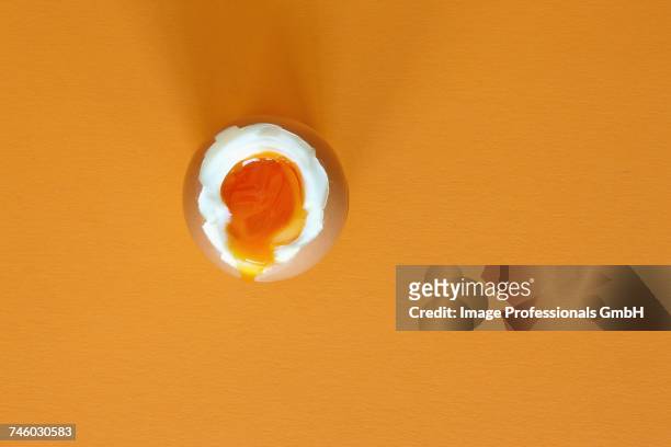 a soft-boiled egg on a yellow surface - gekochtes ei stock-fotos und bilder