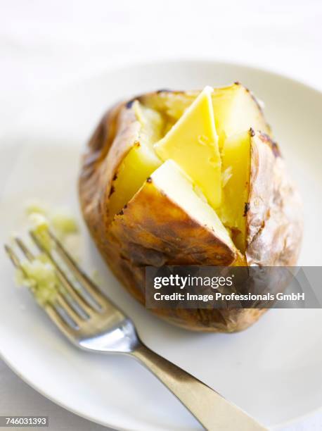 a jacket potato with butter - gepofte-aardappel stockfoto's en -beelden