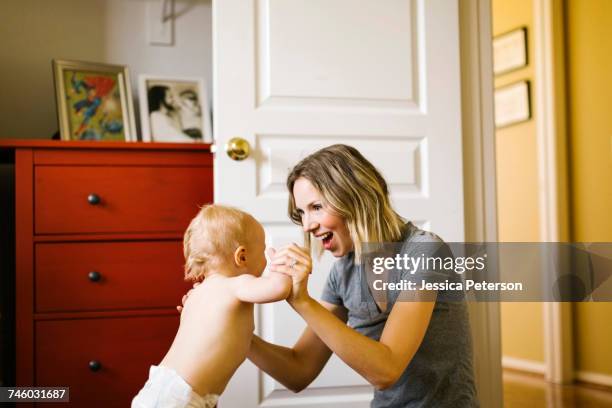 baby boy (12-17 months) taking first steps with mother - diaper boy 個照片及圖片檔