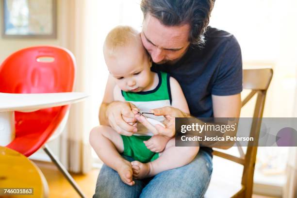 father cutting sons (12-17 months) fingernails - nail scissors - fotografias e filmes do acervo