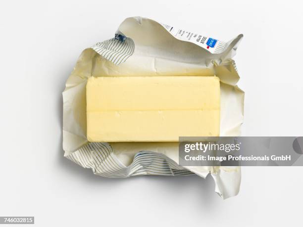 an unwrapped pat of butter on its wrapper - butter stock pictures, royalty-free photos & images