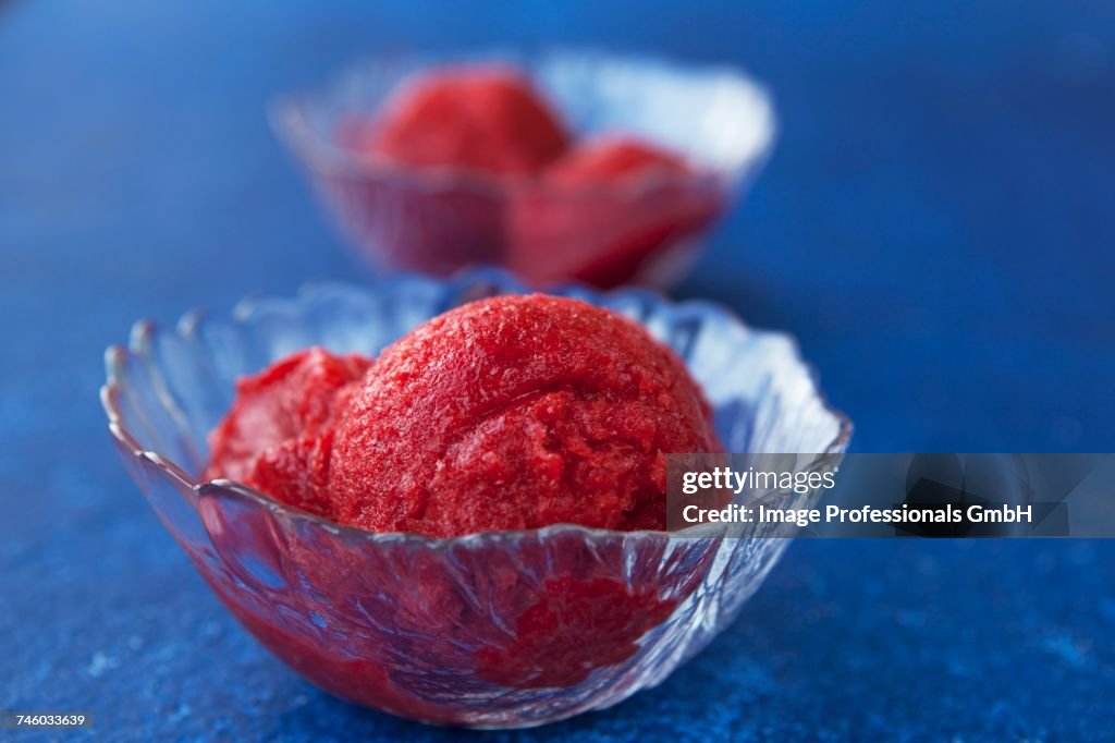 Strawberry sorbet in glass bowls on a blue surface