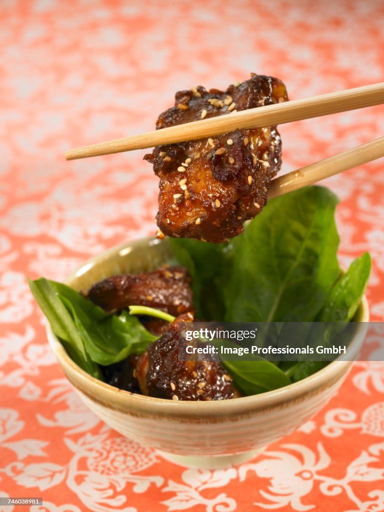 Sweet and sour pork with sesame seeds and spinach shoots