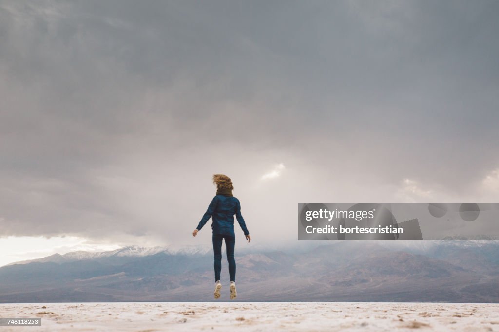 Full Length Of Woman Jumping On Field Against Sky