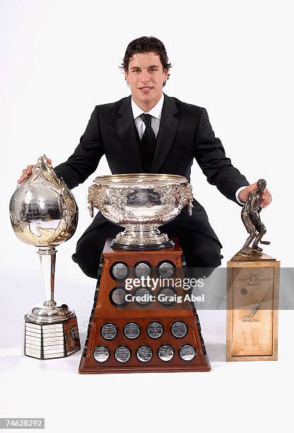 Sidney Crosby of the Pittsburgh Penguins poses for a portrait backstage with the Hart Memorial Trophy, the Art Ross Trophy and the Lester B. Pearson...