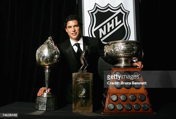 Sidney Crosby of the Pittsburgh Penguins poses for a portrait backstage with the Hart Memorial Trophy, the Lester B. Pearson Award and the Art Ross...