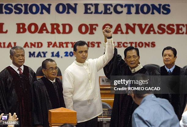 Commission on Elections chairman Benjamin Abalos raises the hand of newly proclaimed senator, detained Philippine navy lieutenant, Antonio Trillanes...