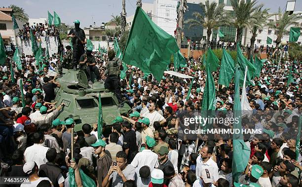 Hamas militants parade on an armoured vehicle belonging to the Fatah-linked Presidential Guard Force 17 exhibited as a war trophy among a crowd of...