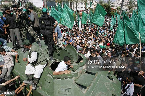 Hamas militants parade on an armoured vehicle belonging to the Fatah-linked Presidential Guard Force 17 exhibited as a war trophy among a crowd of...