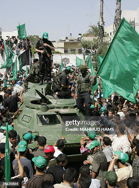 Hamas militants parade on an armoured vehicle belonging to the Fatah-linked Presidential Guard Force 17 exhibited as a war trophy among a crowd of...