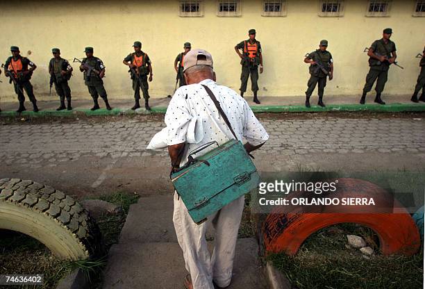 Un anciano lustrabotas se encuentra cerca de agentes de la Policia Nacional Civil y soldados del Ejercito de Guatemala quienes retoman el control de...