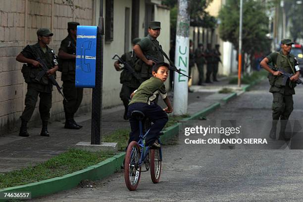 Un nuno pasa con su bicicleta cerca de agentes de la Policia Nacional Civil y soldados del Ejercito de Guatemala quienes retoman el control de Ciudad...