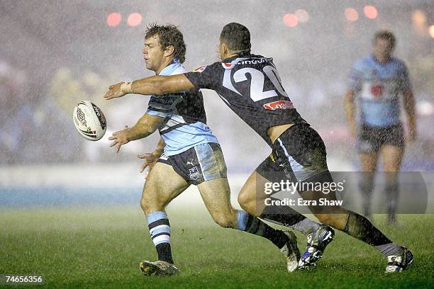 Brett Kimmorley of the Sharks passes the ball before being hit by Louis Anderson of the Warriors during the round 14 NRL match between the...
