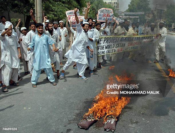 Pakistani activists of Jamiat Tulba Arabia, a student wing of Jamaat-i-Islami party shout slogans in front of a burning effigy of Indian-born author...