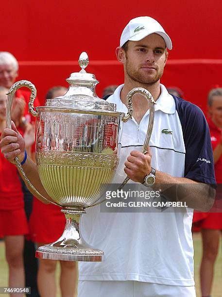 London, UNITED KINGDOM: US Andy Roddick holds his trophy after winning a record equalling fourth Queen's title with a hard-fought three-set victory...