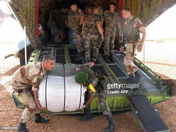 French soldier helps unload a French Airforce transport plane loaded with humanitarian aid at an airstrip just outside Goz Beida, which is 90...