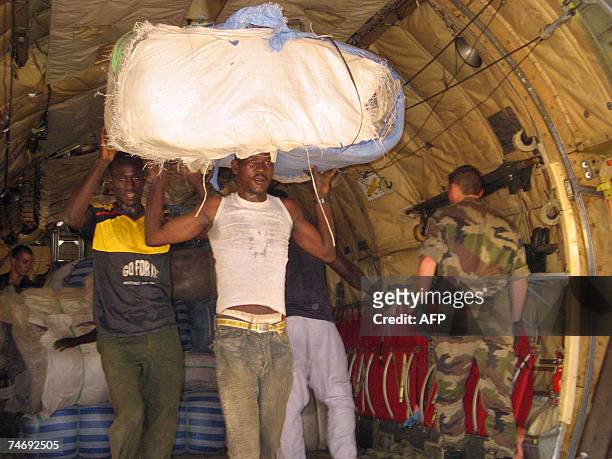 Chadian men help unload a French Airforce transport plane loaded with humanitarian aid at an airstrip just outside Goz Beida, which is 90 kilometres...