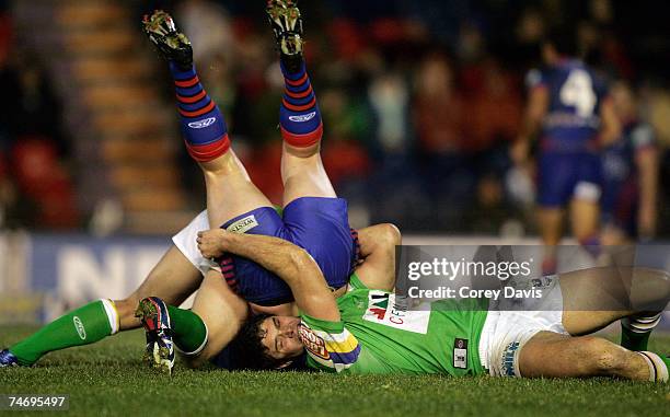 Mitchell Sargent of the Knights is tackled by Raiders defence during the round 14 NRL match between the Newcastle Knights and the Canberra Raiders at...