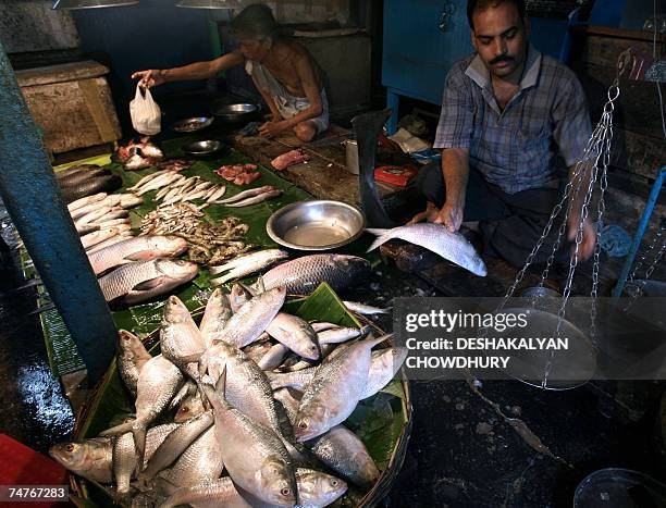 An Indian vendor weighs a Hisla fish, which is regarded by Bengalis as most desirable, at a fish market in Kolkata, 19 June 2007. State ministers...