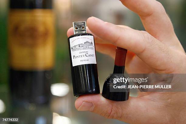 Man shows a promotional USB key in a mini red wine bottle, 19 June 2007 during Vinexpo, the world's biggest wine and spirits trade fair in Bordeaux,...