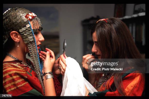 Two women put on lipstick July 15, 1997 in Bethlehem, Israel. Students from Bethlehem University honored their heritage in a fashion show featuring...