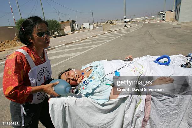 Red Cross official evacuates a critically ill Palestinian woman from the Gaza Strip to a waiting Israeli ambulance June 20, 2007 at Israel's Erez...