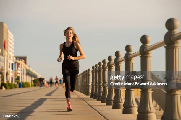 caucasian teenage girl running on boardwalk - boardwalk stockfoto's en -beelden