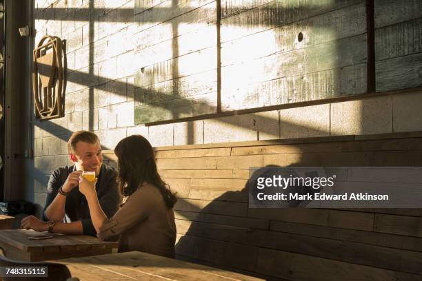 caucasian couple talking in brew pub - café homme vitre photos et images de collection
