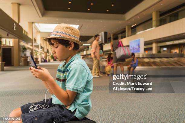 boy playing on cell phone in airport - pre game stockfoto's en -beelden