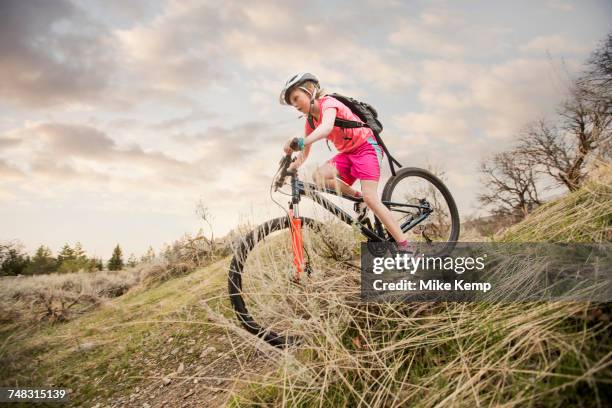 caucasian girl riding bicycle on hill - girl mound stock-fotos und bilder