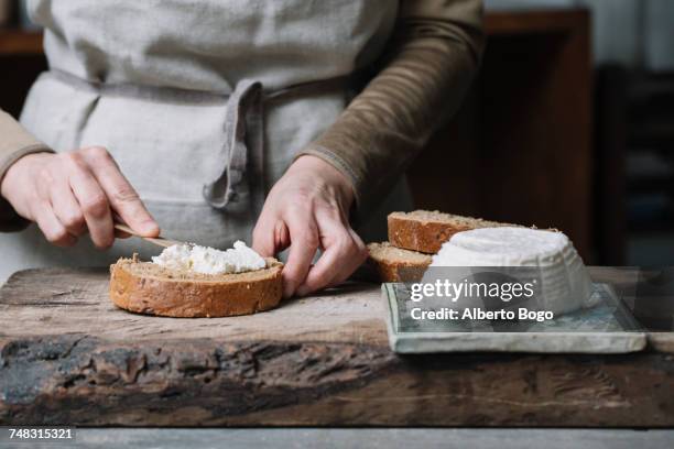 woman spreading ricotta cheese onto slice of bread, mid section - homemade loaf of bread stock pictures, royalty-free photos & images