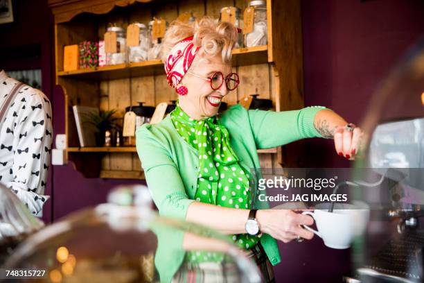 quirky vintage mature woman working behind tea room counter - grüne bluse stock-fotos und bilder
