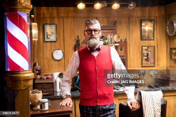 portrait of quirky senior man in traditional old english barber shop - barbier stock-fotos und bilder