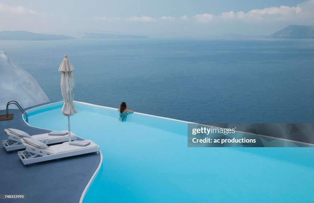 Caucasian woman in infinity pool admiring scenic view of ocean