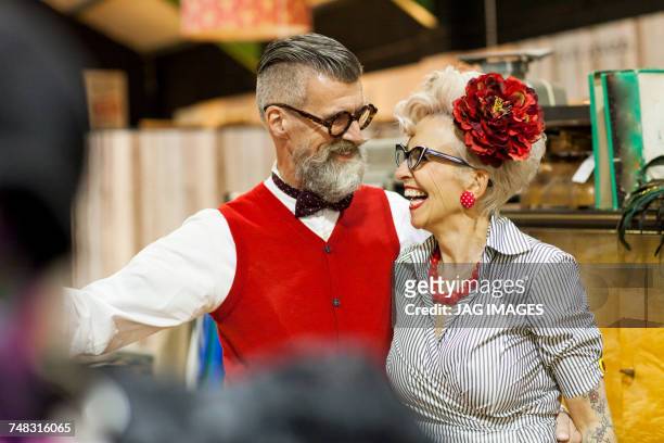 quirky vintage couple laughing and looking at each other in antique emporium - authentic style stock pictures, royalty-free photos & images
