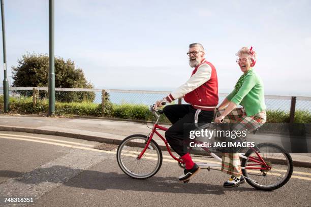 quirky couple sightseeing on tandem bicycle, bournemouth, england - fahrrad paar stock-fotos und bilder