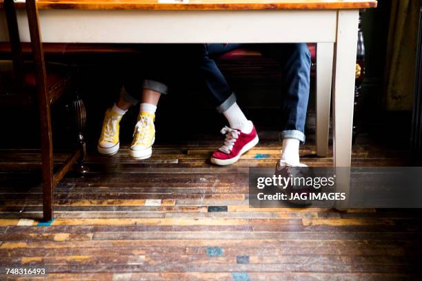 jeans and trainers worn by couple sitting at table - table leg stock pictures, royalty-free photos & images