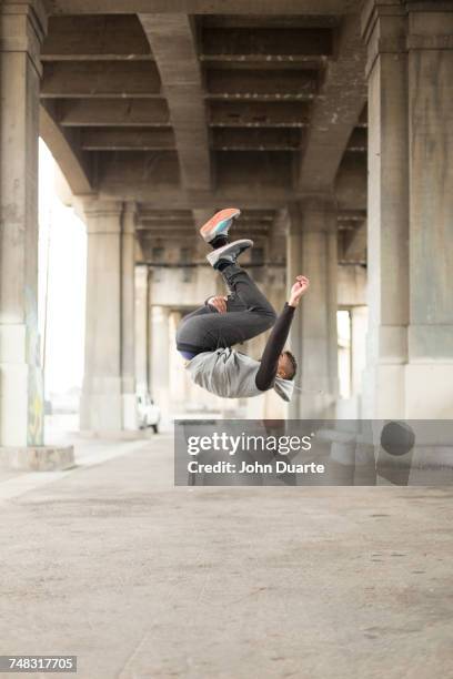 mixed race man jumping upside-down under bridge - underpass stock pictures, royalty-free photos & images