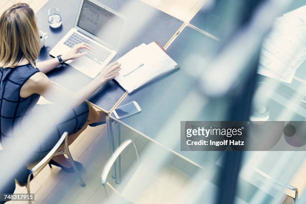 high angle window view of young businesswoman typing on laptop at office desk - munich business stock pictures, royalty-free photos & images