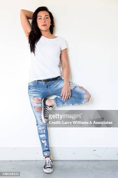 portrait of caucasian woman leaning on wall - zerrissene jeans stock-fotos und bilder