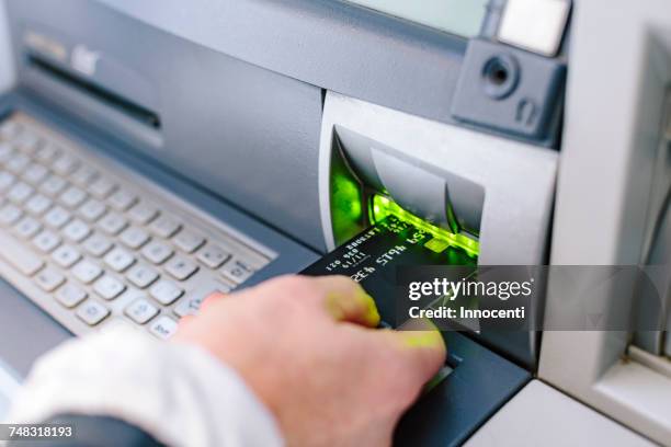 close up of womans hand inserting credit card into cash machine - inserts stock pictures, royalty-free photos & images