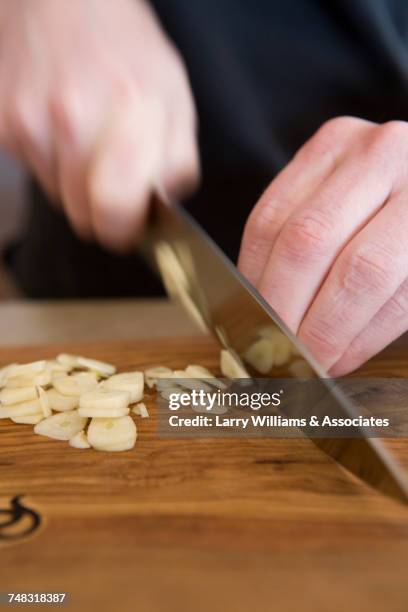 hands slicing garlic with knife - chopping garlic stock pictures, royalty-free photos & images