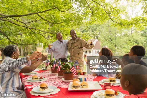 soldier and multi-generation family toasting with lemonade at picnic - 4th of july cookout fotografías e imágenes de stock