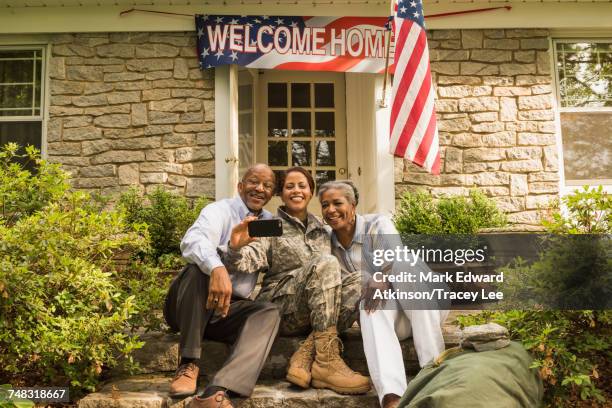 soldier and parents sitting on front stoop posing for cell phone selfie - american indian military stock pictures, royalty-free photos & images