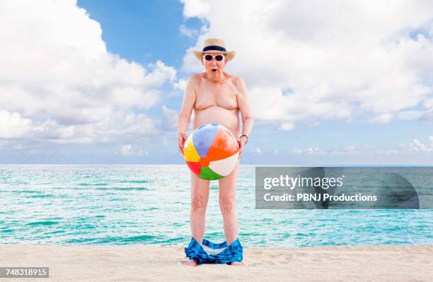 naked older caucasian man covering waist with beach ball - birthday suit stock pictures, royalty-free photos & images