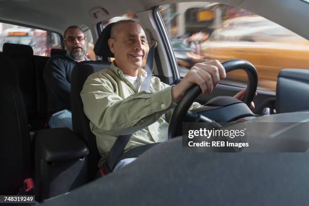 smiling hispanic man driving car with passenger - taxi driver stock pictures, royalty-free photos & images