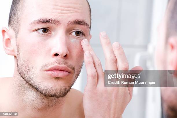 man applying face cream, close-up - man eye cream imagens e fotografias de stock